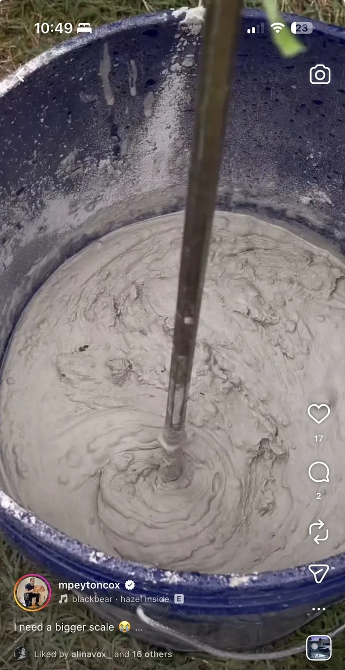 Concrete being mixed in a blue barrel with a paddle mixer, shot from directly above.